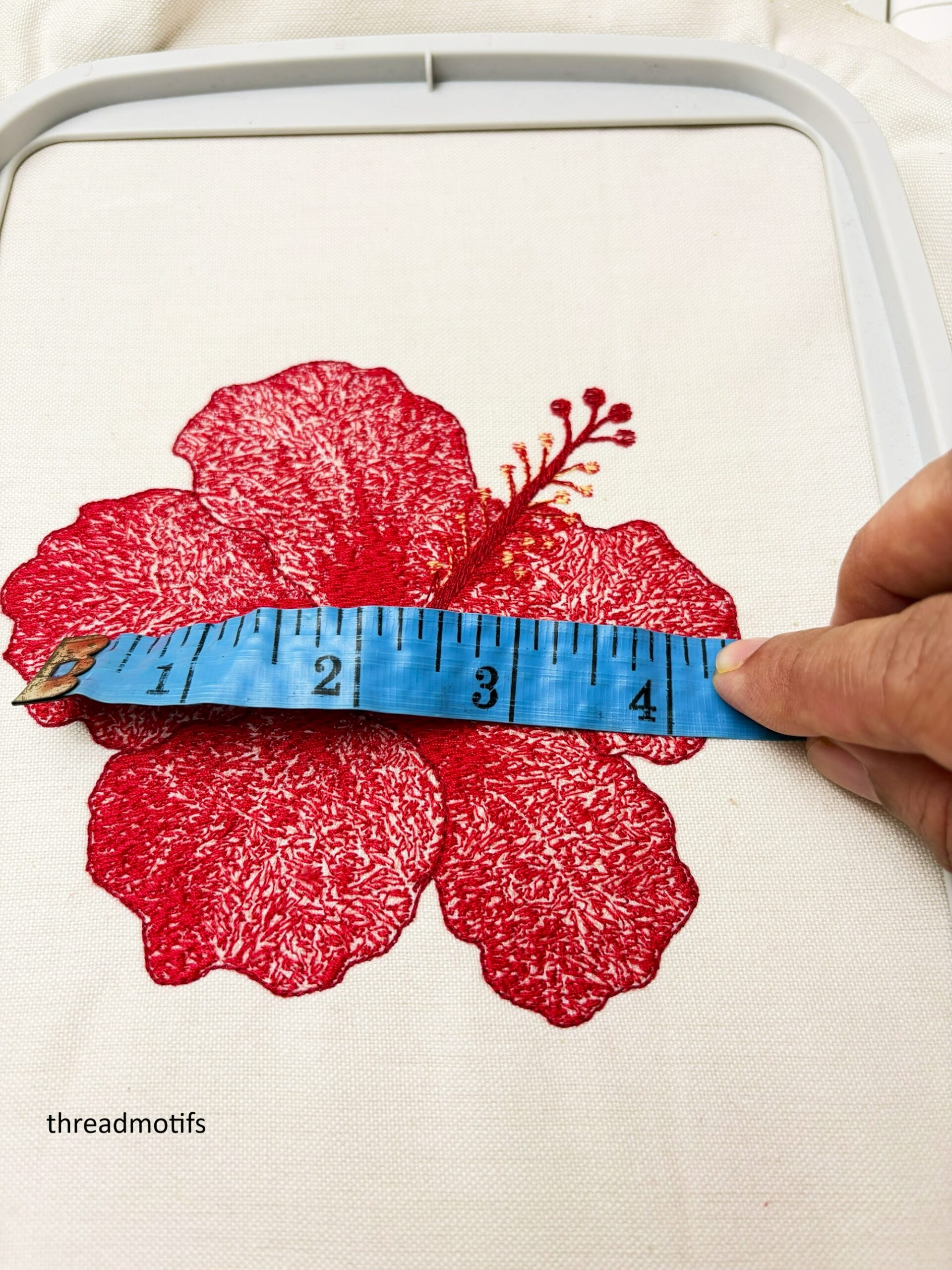 Measuring tape over the hibiscus embroidery design embroidered on fabric